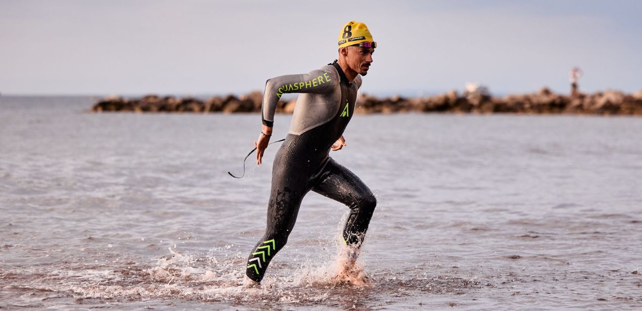 Clément Mignon running in Aquasphere wetsuit and yellow swim cap