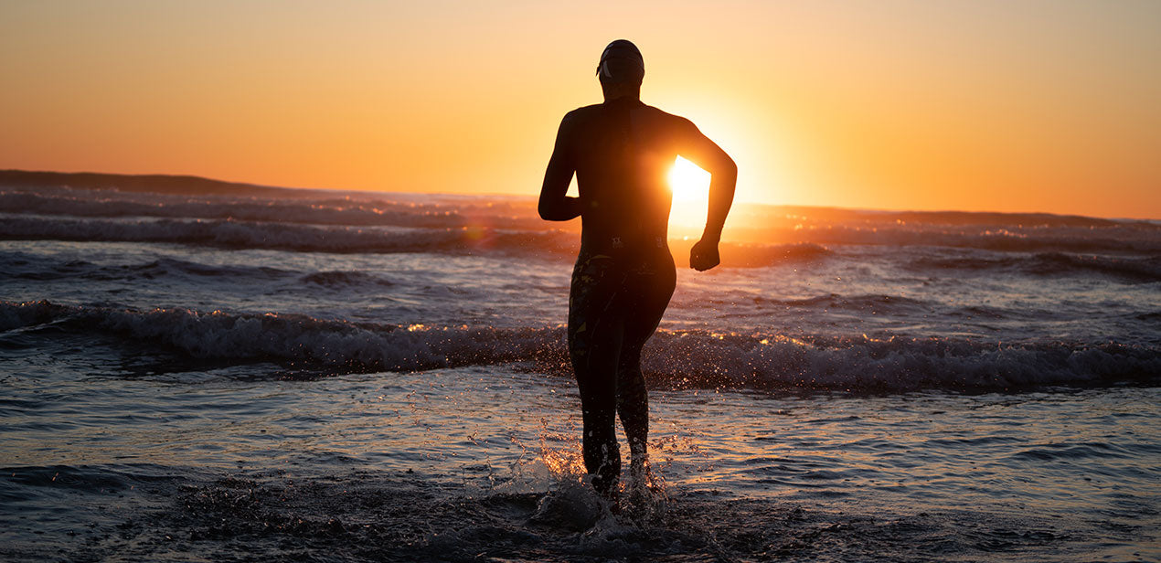 Sam Long running in Aquasphere wetsuit towards sunset.